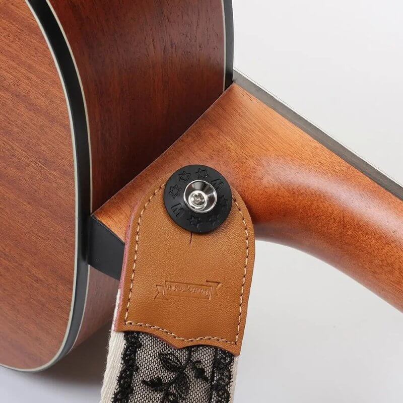 Ansicht der Befestigung des schwarzen Gitarrengurts mit floraler Spitze